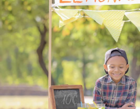 little boy smiling at his lemonade stand