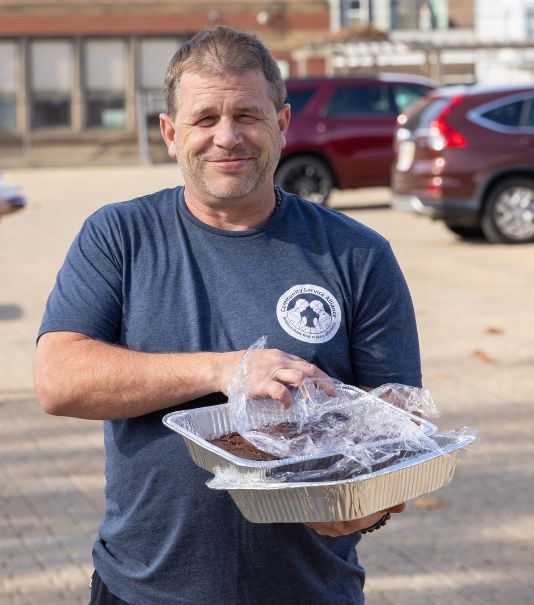 man at bbq holding container of food